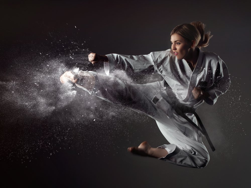 A martial artist in a white gi throwing a flying kick