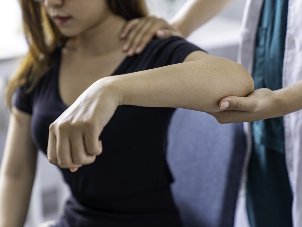 A physical therapist assessing a patient's arm and elbow mobility