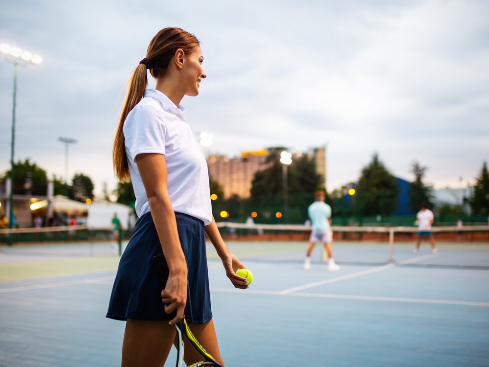 A woman holding a tennis racket and ball on a court