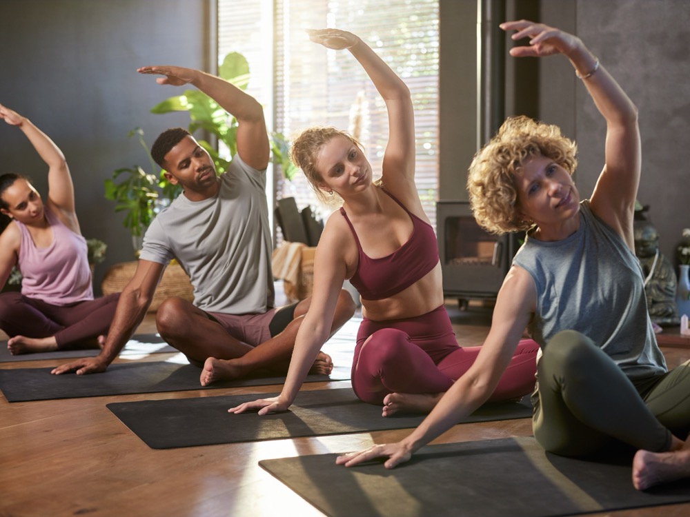 A group yoga class doing a seated side stretch